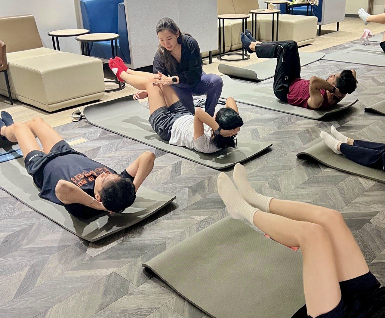 Pamela guiding a team through a mat Pilates session at their office
